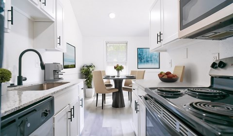 a kitchen with white cabinets and stainless steel appliances and a table with chairs